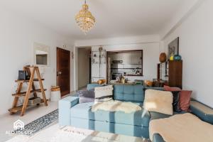 a living room with a blue couch and a kitchen at Nomad's Surf and Sunset Haven - Ocean View in Santa Cruz in Santa Cruz