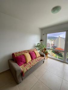 un sofá en una sala de estar con una gran ventana en Loft céntrico y moderno con vista al lago, en San Carlos de Bariloche