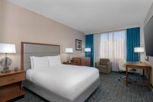 a bedroom with a large white bed and a desk at DoubleTree by Hilton Hotel West Palm Beach Airport in West Palm Beach