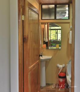 Un baño con puerta de madera y lavabo. en Laughing Falcon Studio, en El Castillo de La Fortuna