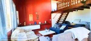 a living room with blue couches and a red wall at Guirigay CASA CON PISCINA in Muros de Nalón