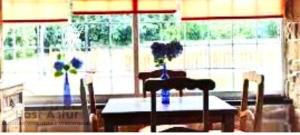 a dining room table with two chairs and two vases with flowers at Guirigay CASA CON PISCINA in Muros de Nalón +12 photos