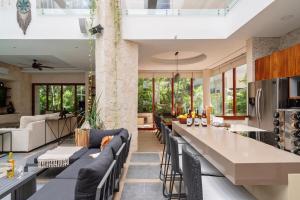 a kitchen and living room with couches and a bar at 9Br Luxury Villas Aldea Zama, Private Pools & Gym! in Tulum