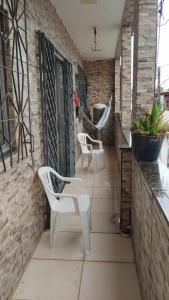 een terras met twee witte stoelen en een hangmat bij Casa Mussurunga in Salvador