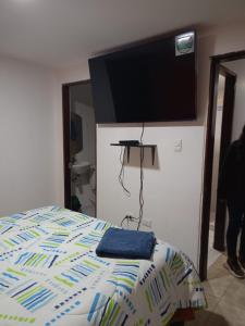 a bedroom with a bed with a flat screen tv on the wall at Ipiales puerta de oro in Ipiales