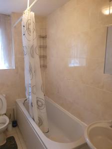 a bathroom with a tub and a toilet and a shower curtain at Four Large Double With Ensuites in Abbey Wood +2 photos