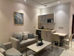 a living room with a couch and a kitchen at شقق البيلسان الذهبي للشقق المخدومة - اقتصادي in Quai