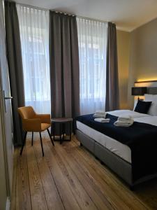a bedroom with a bed and a chair and windows at Landhaus Villa Daheim in Heiligenhafen +10 photos