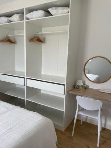 a white bedroom with a mirror and a bed at Casinha de Roliça in Roliça