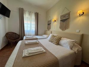a hotel room with two beds with towels on them at Quartos Abelha in Porto Covo