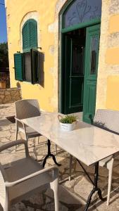 a table and chairs in front of a building with a green door at Skandalis Apartments with pool in Chorafakia +189 photos