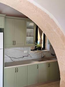 an archway in a kitchen with white cabinets and a sink at Skandalis Apartments with pool in Chorafakia