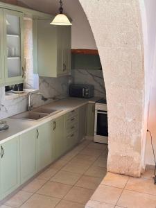 a kitchen with green cabinets and a stone wall at Skandalis Apartments with pool in Chorafakia