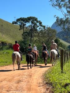 a group of people riding horses down a dirt road at Hotel Fazenda Pedra Selada Rural in Visconde De Maua