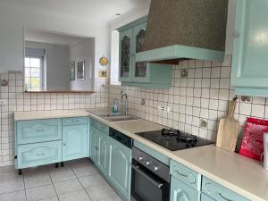 a kitchen with blue cabinets and a sink and a stove at Maison à Lilia in Plouguerneau +23 photos