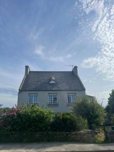 a white house with a gray roof and a sky at Maison à Lilia in Plouguerneau