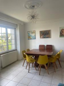 a dining room with a wooden table and yellow chairs at Maison à Lilia in Plouguerneau