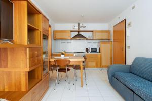 a kitchen with a table and a blue couch at L'Angolo Fiorito con terrazza e in pieno centro in Grado