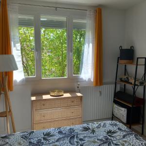 a bedroom with a bed and a dresser and two windows at PARIS CDG Chantilly Senlis in Senlis