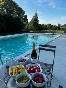 a table with food and a bottle of champagne next to a swimming pool at Chateau de Maisonneuve in Leigné-les-Bois