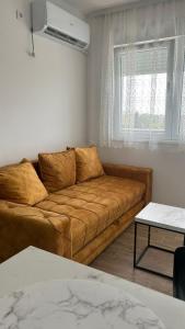a living room with a brown couch and a window at Stan na dan Indjija in Inđija