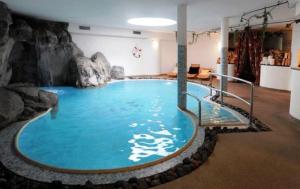 una grande piscina in una stanza con parete di roccia di Hotel Henriette a Malè