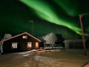 a house with the green northern lights in the sky at Villa Åberg, Kuivaniemi in Ii