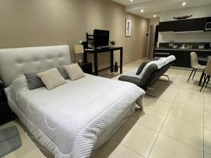 a bedroom with a white bed and a kitchen at Luxury Loft Condominiums Hotel Wyndham Nordelta in Benavídez