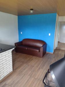 a brown couch in a room with a blue wall at Loft 4 Sítio Cachoeiras do Caledônia in Nova Friburgo
