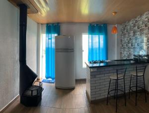 a kitchen with a refrigerator and a counter with blue curtains at Loft 4 Sítio Cachoeiras do Caledônia in Nova Friburgo