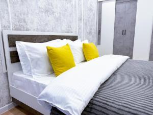 a bed with yellow and white pillows in a room at ЖК Nomad KZ Almaty in Zhezdi