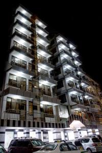 um edifício alto com carros estacionados em frente em Sleep Inn Hotel - Kariakoo em Dar es Salaam