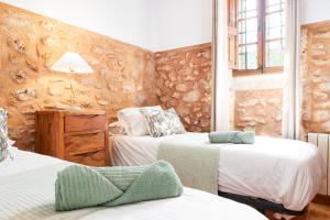 1 Schlafzimmer mit 2 Betten und einer Steinmauer in der Unterkunft Casa Antigua in Santanyi + 26 Fotos