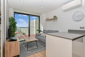 a kitchen and living room with a couch and a clock at Stylish Apartment with Pool, Spa and Gym in Gibraltar