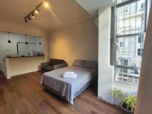 a bedroom with a bed and a couch and a window at Studio SDU Aeroporto VLT Metrô Cinelândia in Rio de Janeiro