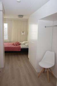 a bedroom with a bed and a white chair at Lahti City Home 1 in Lahti