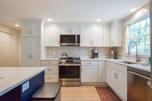 a kitchen with white cabinets and stainless steel appliances at Beach Getaway with Private Backyard in Orleans