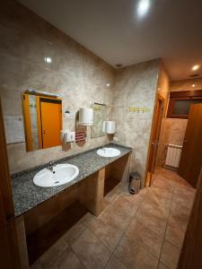 a bathroom with two sinks and a mirror at Albergue de peregrino Cruz de Fierro in Foncebadón