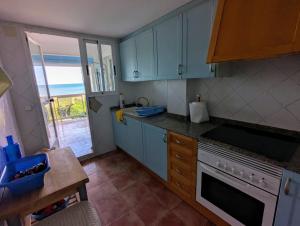 a kitchen with blue cabinets and a view of the ocean at Terraza con Mar in Xeraco