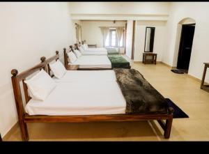 a row of four beds in a room at Karuniagiri Guest House in Jāmb