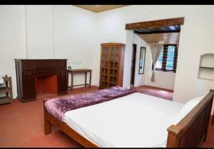 a bedroom with a large bed and a fireplace at Karuniagiri Guest House in Jāmb