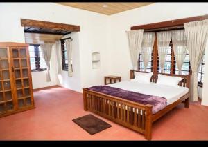 a bedroom with a large bed in a room with windows at Karuniagiri Guest House in Jāmb