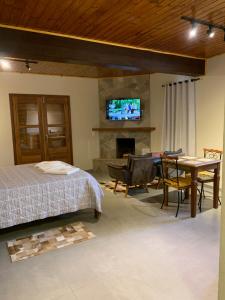 a bedroom with a bed and a table and a television at Chalé Vista Verde in Monte Verde