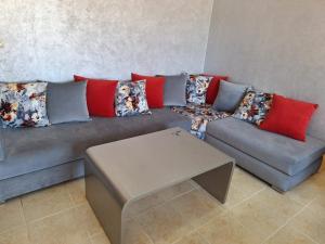 a couch with pillows and a table in a living room at Agadir fadissa in Agadir +1 photo