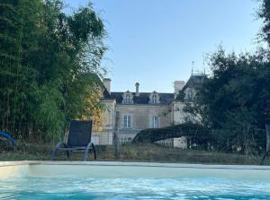 a chair in front of a house with a swimming pool at Chateau de Maisonneuve in Leigné-les-Bois