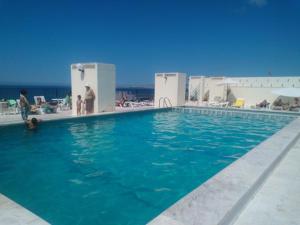 a blue swimming pool with people standing around it at Apartment Qiu in Costa da Caparica