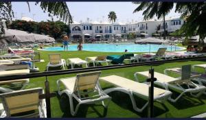 a group of lawn chairs and a swimming pool at Home Wellness in Playa del Ingles