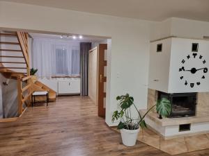 a living room with a fireplace and a clock on the wall at Orzechowy Dom in Trzebnica