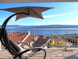 a balcony with a chair and an umbrella at Apartment Delic in Crikvenica