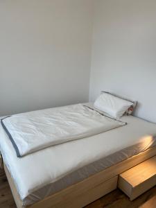 a bed with white sheets and a wooden platform at Living 7 Apartments in Neufahrn in Niederbayern